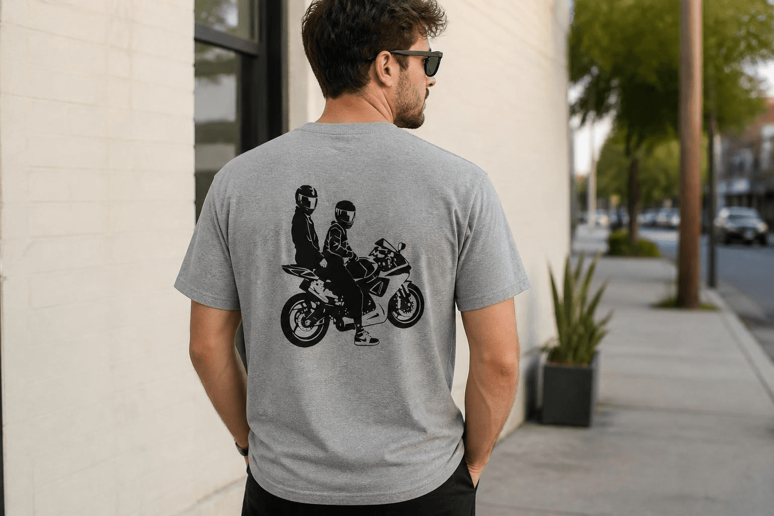 Man wearing a grey t-shirt with a black graphic of two people on a motorcycle.